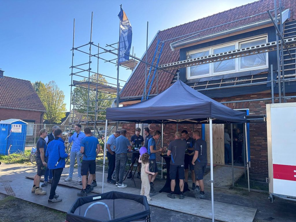 Medewerkers van Webbink Bouwgroep vieren het bereiken van het hoogste punt van de nieuwbouwwoning van Roderick tijdens de bouwfase.